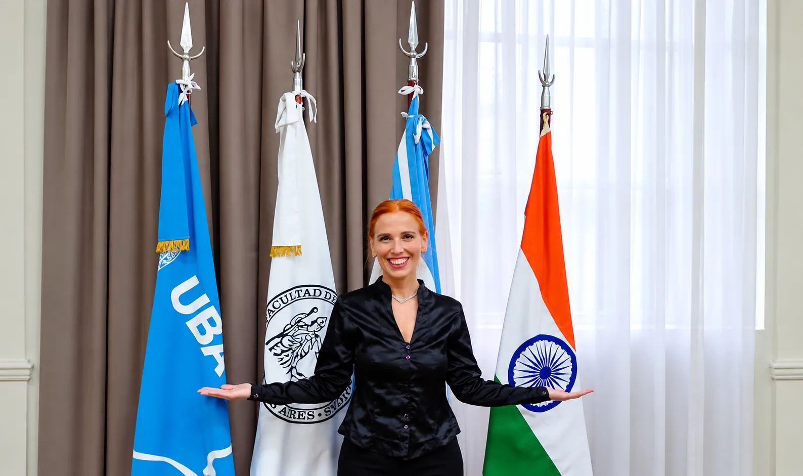 Silvina Draiman, directora y fundadora del Instituto Ayurveda de Argentina, frente a las banderas de la UBA, la Argentina y la India